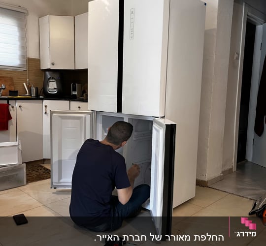 אדם מתקן מקרר עם מברגה חשמלית על הרצפה